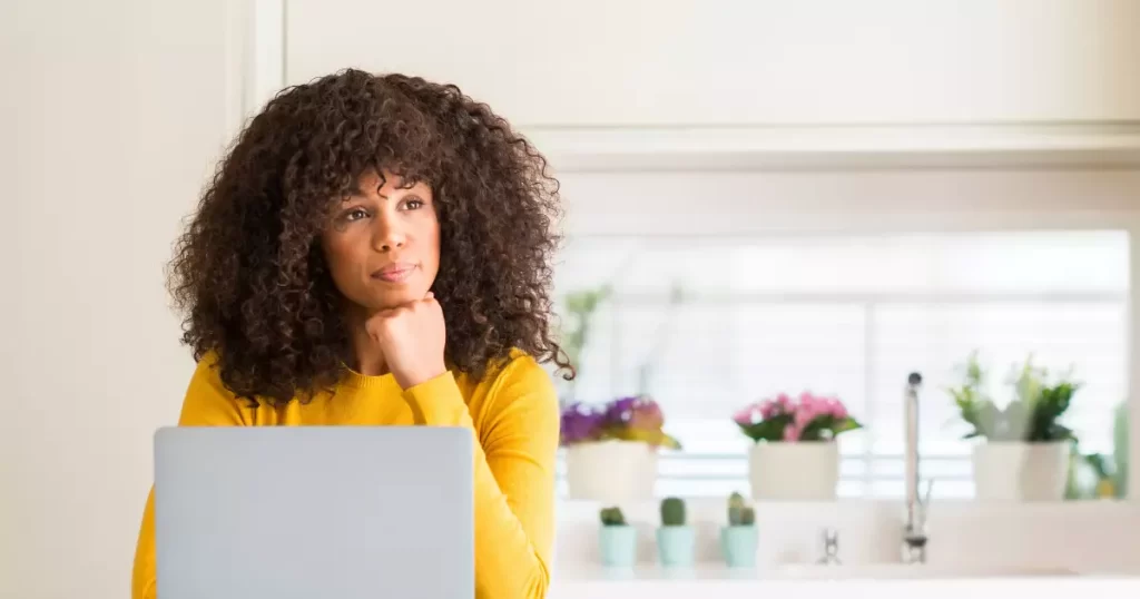 Woman at computer looking off with a question